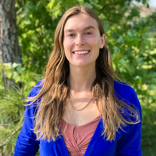 Woman with long blonde hair smiling, wearing a blue cardigan.