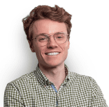 Smiling man with reddish-brown hair wearing glasses and a green and brown checked shirt.